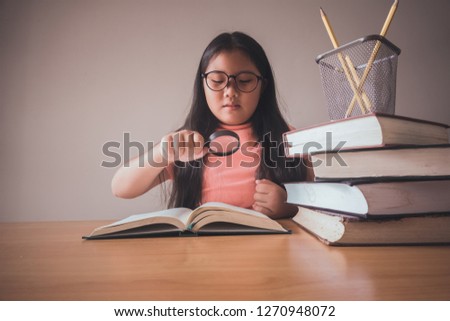 A small female student smiling in the classroom glasses in the form of educational materials and creative elements. Back to school