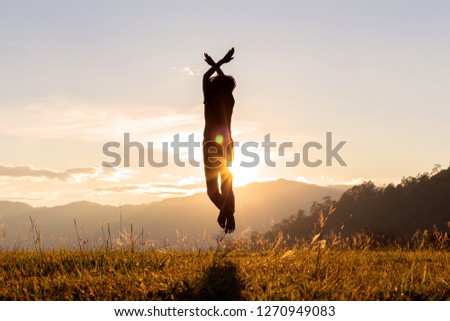 Silhouette of happy child jumping playing on mountain meadow at sunset time