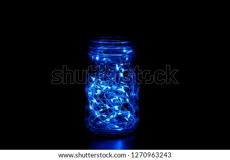 Blue fairy light in a mason jar, in the dark, low-key photography