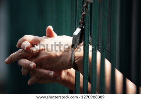 hand of prisoner in jail background.