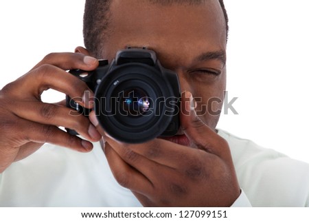 Attractive black guy making a picture with his camera. All on white background.