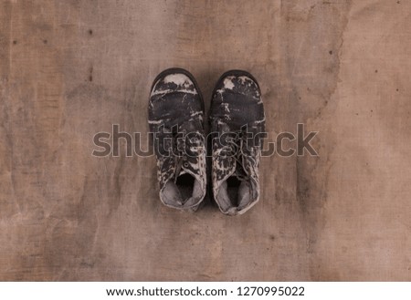 old black worn boots on a brown dirty background