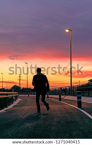Silhouette of young man exercising against idyllic sky line at sunset