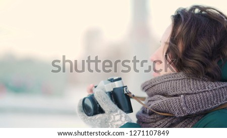 Cute young woman taking picture. Beautiful young woman taking pictures in the city in winter