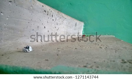 Texture, wallpaper, background of small debris and dust on old gray concrete stairs against a green wall in public or residential buildings in the middle of a cloudy day.