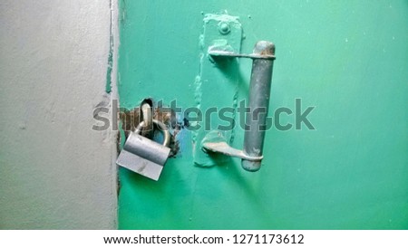 Background, texture, wallpaper of an old green closed metallic door with a handle with a brick or concrete wall in public or residential buildings.