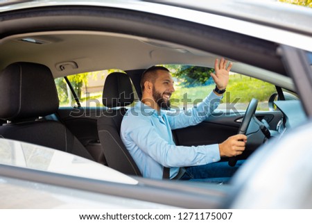 Content young businessman driving a car, shaking hand.