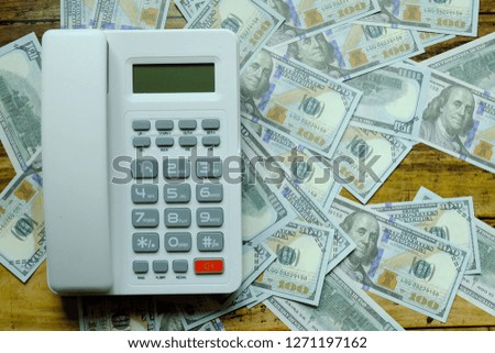 Top view of concept telephone lying on a dollar banknote.