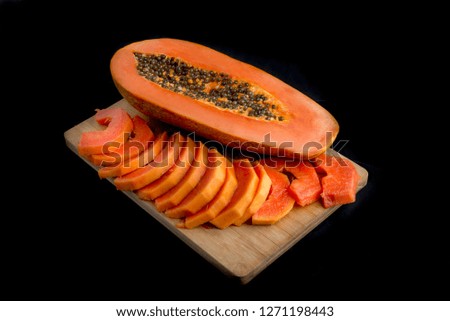 slices of papaya on cutting board in a black background