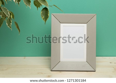 gray frame with plant on  desk near green wall