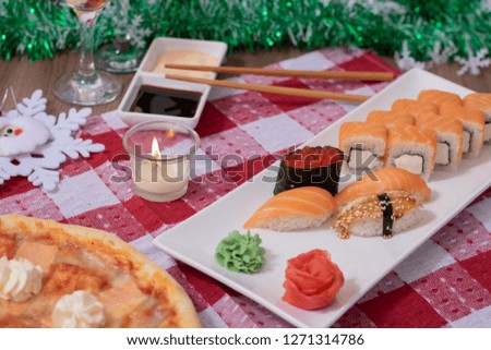 sushi rolls and pizza with wine and fir tree branch on christmas table