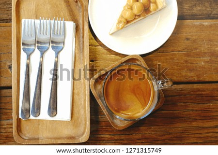 Pictures viewed from the top of hot coffee, macadamia cake and cutlery placed on a wooden table