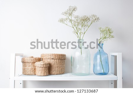 home interior decoration: the branches in vintage bottles and baskets on white shelves