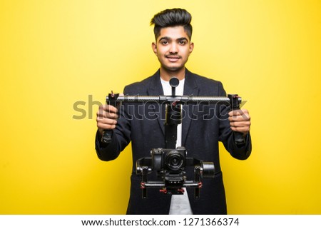 Professional man videographer with gimball video slr isolated on yellow background