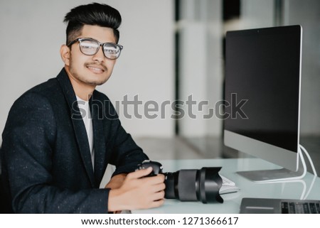 Side view portrait of young photographer sitiing near computer editing photos at desk at home, copy space