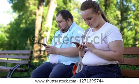 Obese young couple chatting in social networks during date, shy and insecure