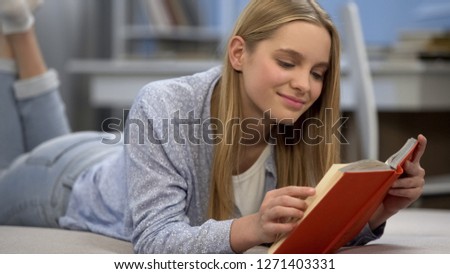 Teenage girl reading book, dreaming of romantic love, imagining heroic man Royalty-Free Stock Photo #1271403331