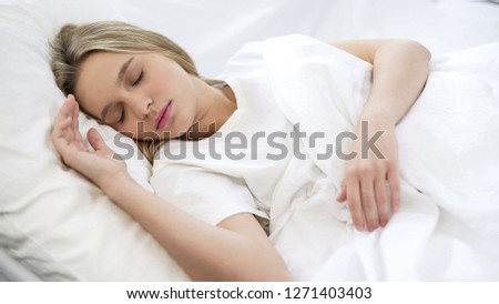 Young pretty female sleeping quietly in bed, comfortable orthopedic mattress