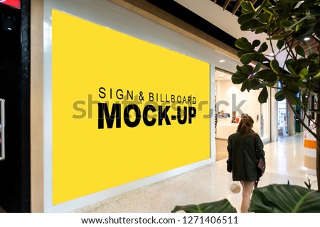 Mock up large blank yellow screen vertical billboard with clipping path at glass on front of showroom in shopping mall near hallway, perspective with empty space for advertising information

