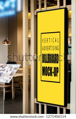 Mock up large blank yellow screen tall billboard or vertical signboard near entrance of restaurant with clipping path and blurred menu sheet in background, empty space for advertising or information

