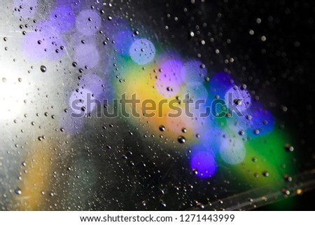 close up Blur rain drops on transparent umbrella in Autumn with Bokeh colour full purple light. Abstract background. 