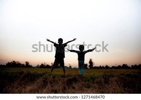 Two children standing together in the evening