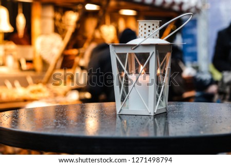 A white lantern with candle inside on the background of a market stall