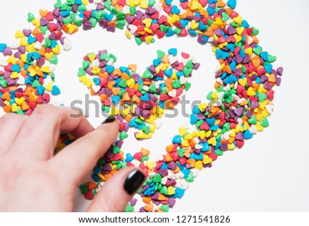 Colorful little hearts on white background. Female hands makes a shape heart.
