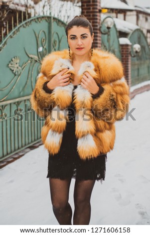 Elegant arabic woman in fox fur coat and black dress outdoors, vintage style. Concept of femininity and lady's grace 