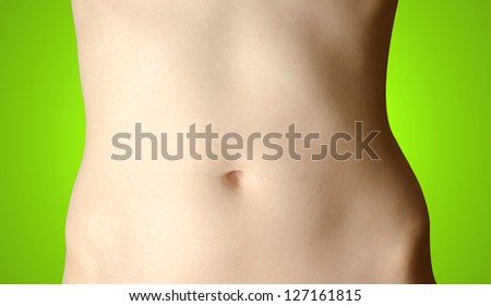 Stomach. Beautiful female body isolated on green background. Young woman stomach with shadow on left side.