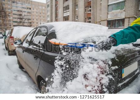 man cleaning his car after snow storm. winter time