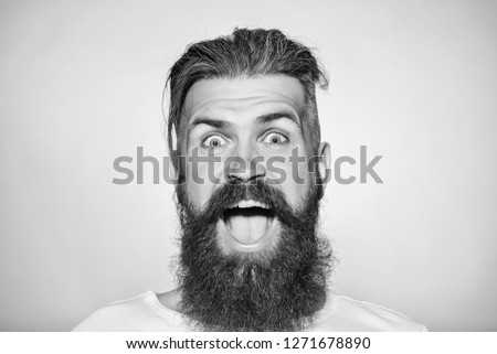 handsome young man with long beard and moustache on smiling happy face on grey background in studio
