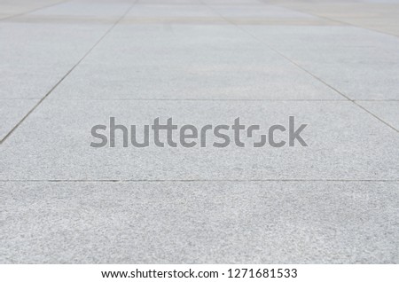 Gray granite paving slab. Photo with perspective. Selective focus. A large pattern of sidewalk tiles for pedestrians.