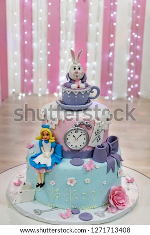 Birthday party cake Alice in Wonderland, marzipan rabbit, bunny in the cup with saucer, clock, keys, bow,  cake decorations, fairy  tale theme