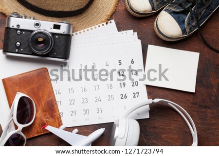 Travel vacation concept with accessories, headphones, beach hat, camera, passport, airplane toy, calendar and photo frame. Top view with copy space. Flat lay