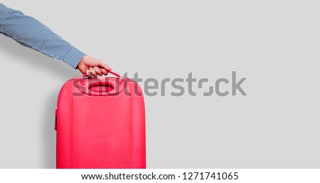 The man is giving by hand A red travel suitcase on wheels, isolated on a white background. Travel concept, packing up before departure. Preparing for travel, going on vacation, break, rest.