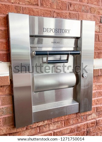 The 24-hour drive-thru night depository terminal of a neighborhood bank set on red brick wall in a vertical image format. Royalty-Free Stock Photo #1271750014
