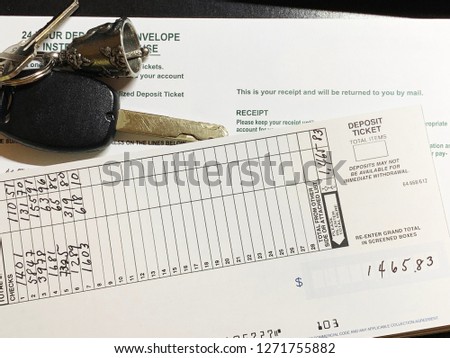 A collage of bank deposit slip with written numbers and a deposit envelope with car keys on a pewter bell keychain.