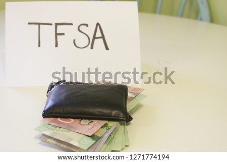 a sign that says TFSA next to a wallet that has money in it. Theme of Canadian savings. TFSA stands for tax free savings account