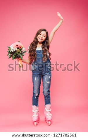 adorable smiling child in roller blades with flower bouquet raising hand on pink background