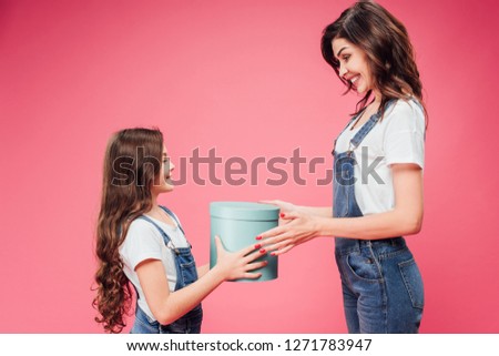 daughter giving present to mother on mothers day isolated on pink 