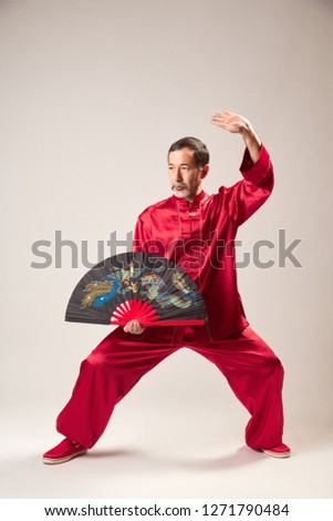 Senior master practicing qi qong taijiquan at studio. Breathing exercise and martial art moves, traditional chinese qi energy management gymnastics