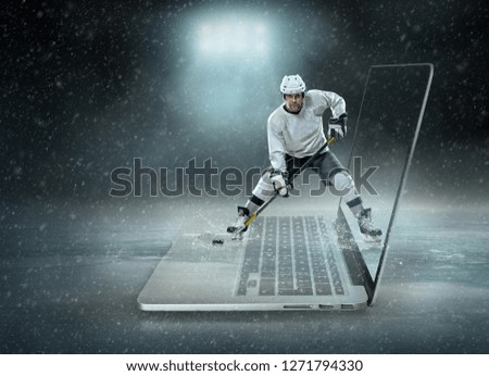 Caucassian ice hockey Player in dynamic action in a professional sport game play on the laptop in hockey under stadium lights.