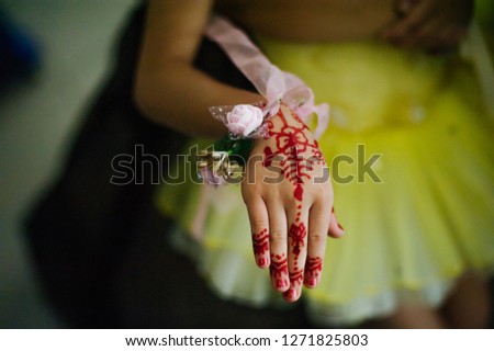 focus on beautiful asian teen girl's hand with red henna drawing, asian girl in blur background.