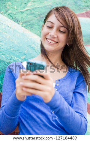 happy cute teenage girl text messaging smiling with joy. vertical shot