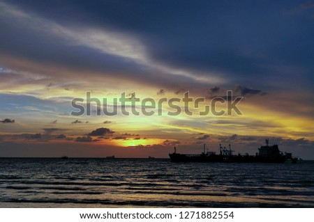 Beach with views sunset of the backdrop of a cargo ship anchored