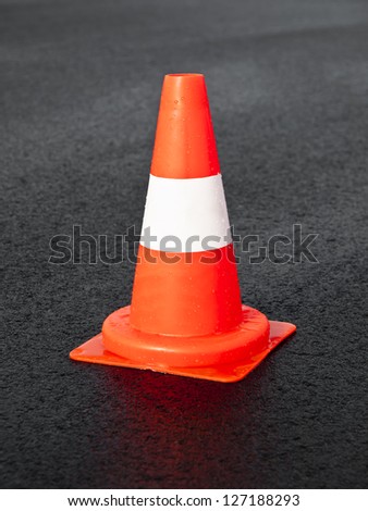Wet traffic cone on a black asphalt