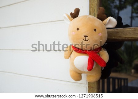 A brown deer stuffy doll hanging on a door.