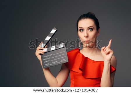 Elegant Actress in Red Dress Holding Cinema Clapboard. Glamorous television host ready to start a show 
