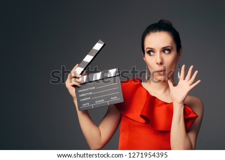 Elegant Actress in Red Dress Holding Cinema Clapboard. Glamorous television host ready to start a show 
